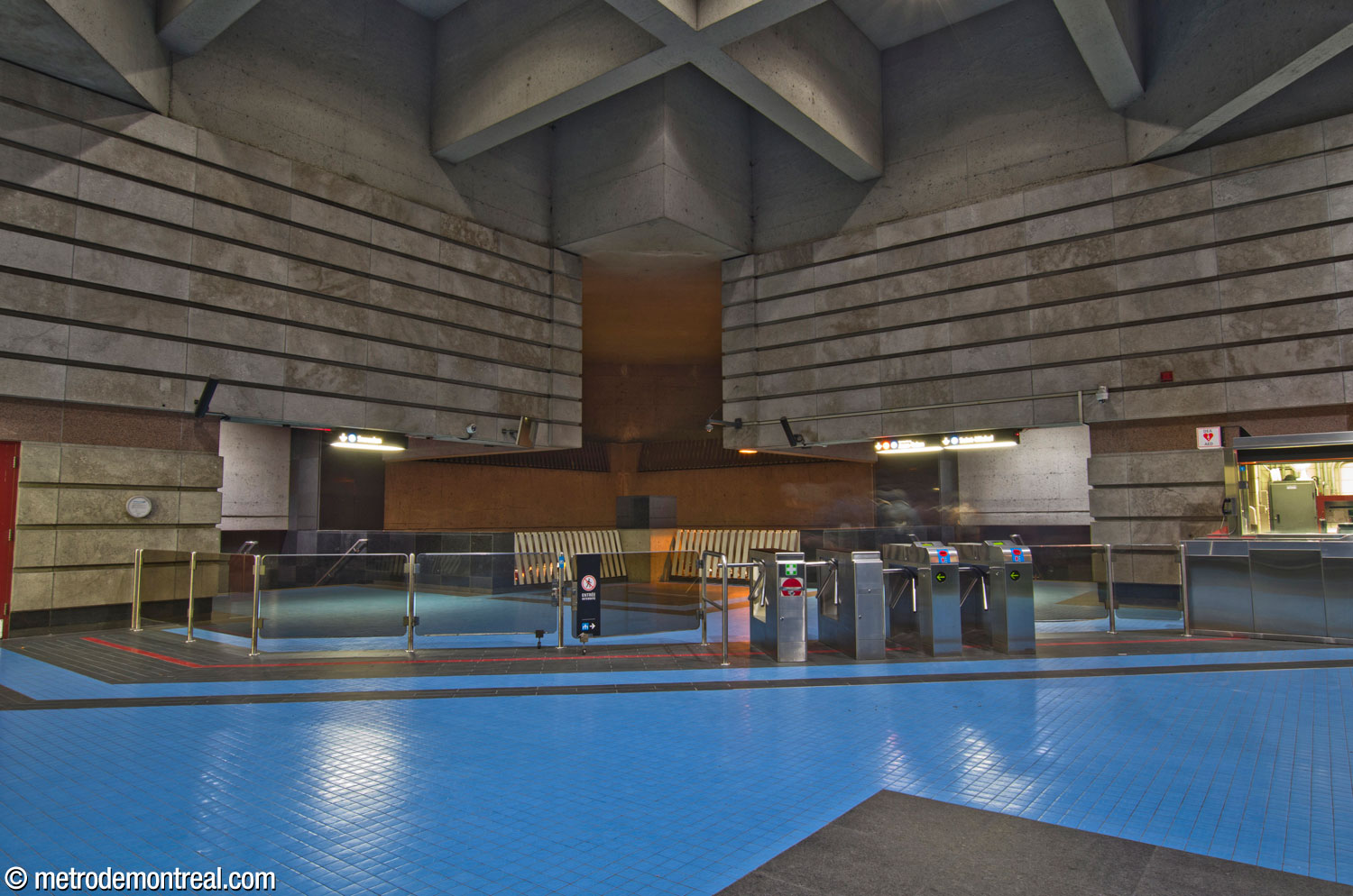 The ticket hall looking north toward the gateline, the stairs to the platforms, and between them, the overlook onto the platforms. Above that is a shadowy space that houses a ventilation shaft.
