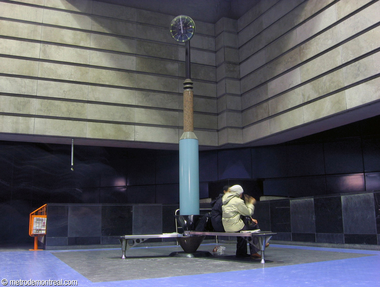 Météore Design's sculptural tall clock, Lieu de rendez-vous, in pink and black granite and light blue enamelled steel. The stainless steel benches mimic the hands of a clock against the circle inscribed in the black granite floor of the ticket hall.