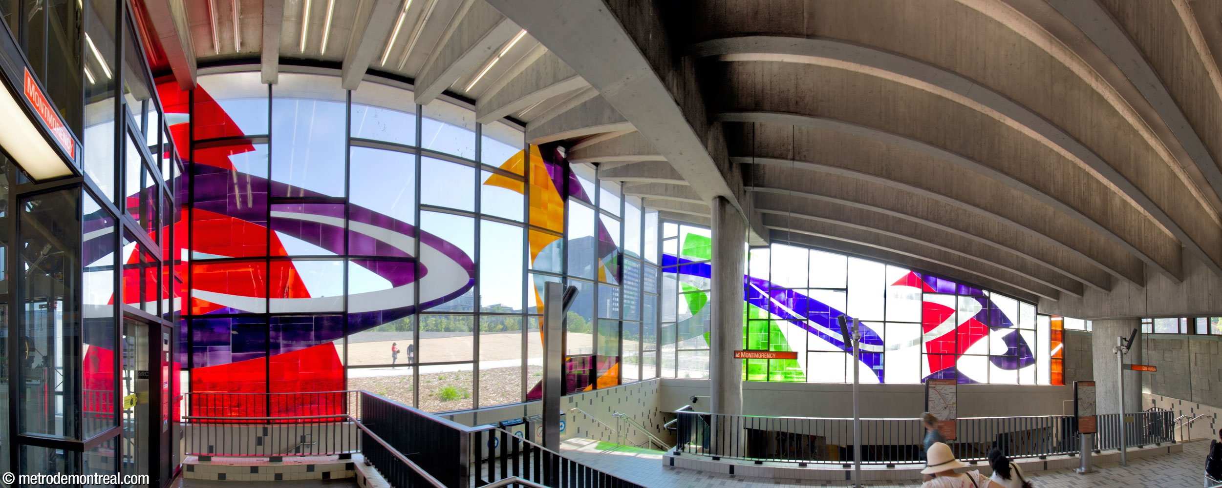 Marcelle Ferron’s stained-glass window on the south and west walls of the headhouse, seen from within the fare-paid zone, on the upper level of the ticket hall. The elevator shaft to the Montmorency platform is at left. At right, the lower level of the ticket hall overlooks the trainroom and leads to the stairs to the platforms.