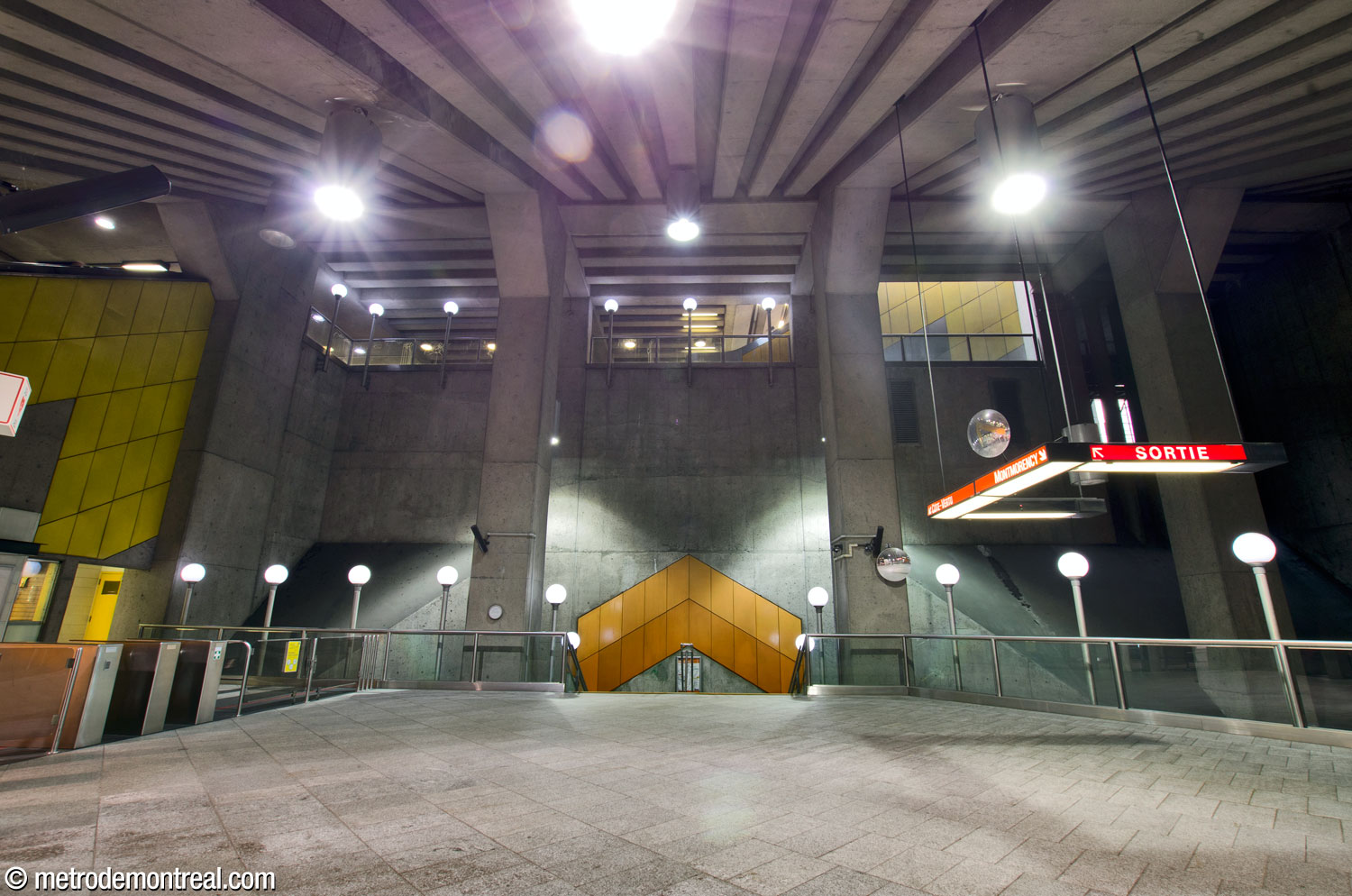 The eastern wall of the station's main volume, facing the head of the stairs to the Côte-Vertu platform below. The walkway between the headhouse and main escalator is visible above.