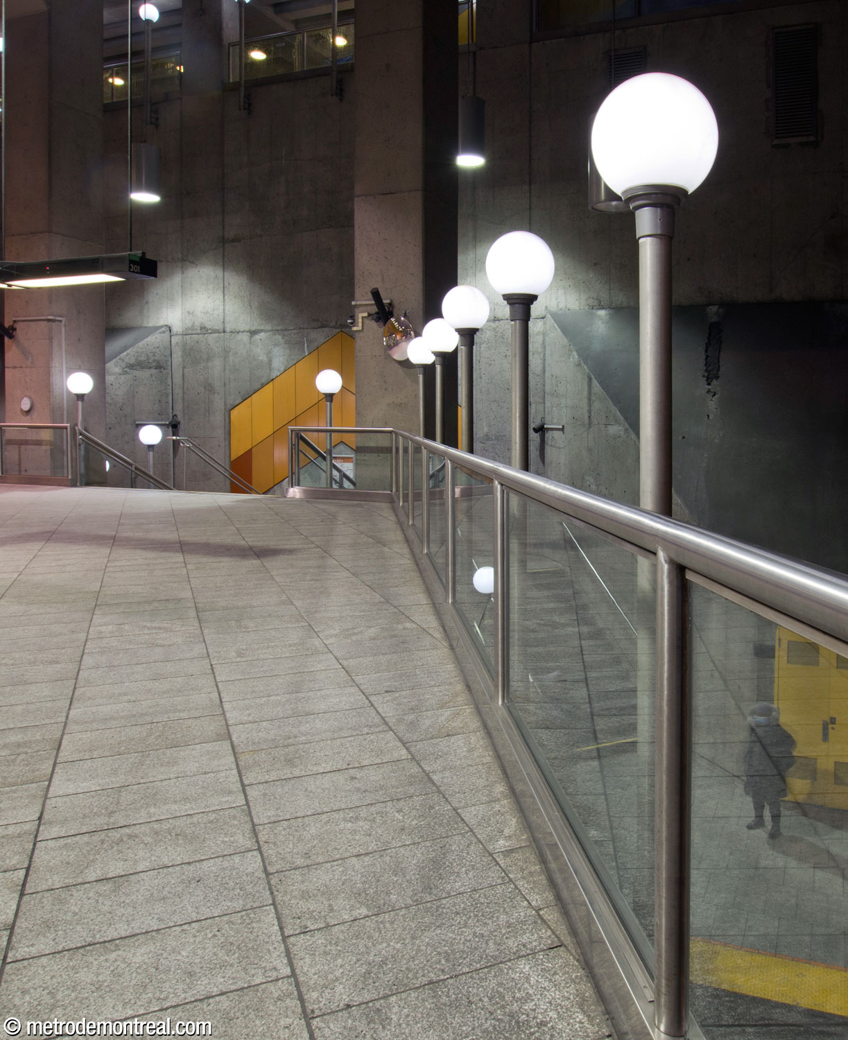 A row of the station's signature globe-shaped lamps, along the edge of the mezzanine above the tracks.