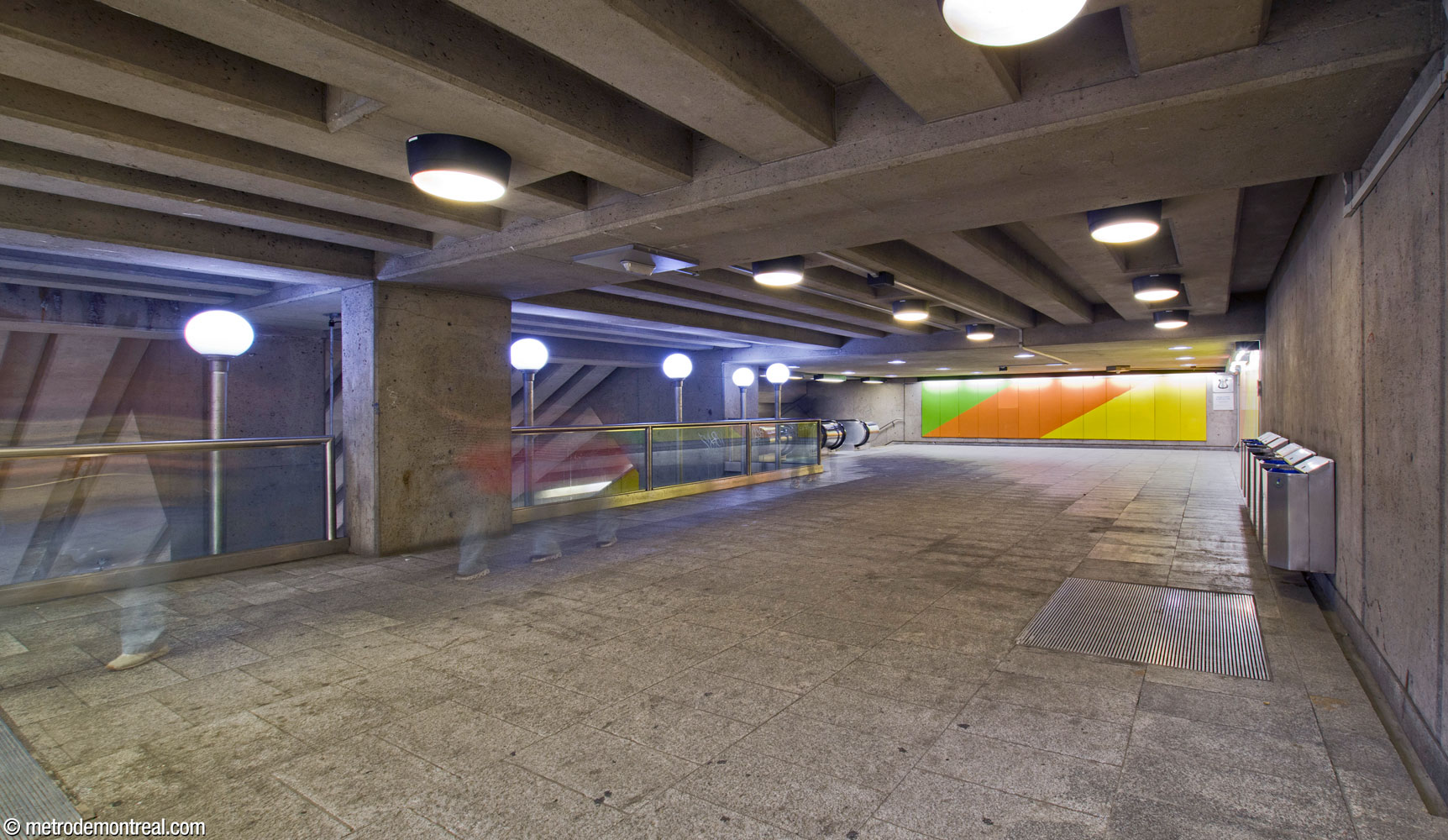 View along the walkway over the main volume, looking north toward the head of the escalators to the ticket hall. At the end of the hall is a mural by Gilbert Sauvé.