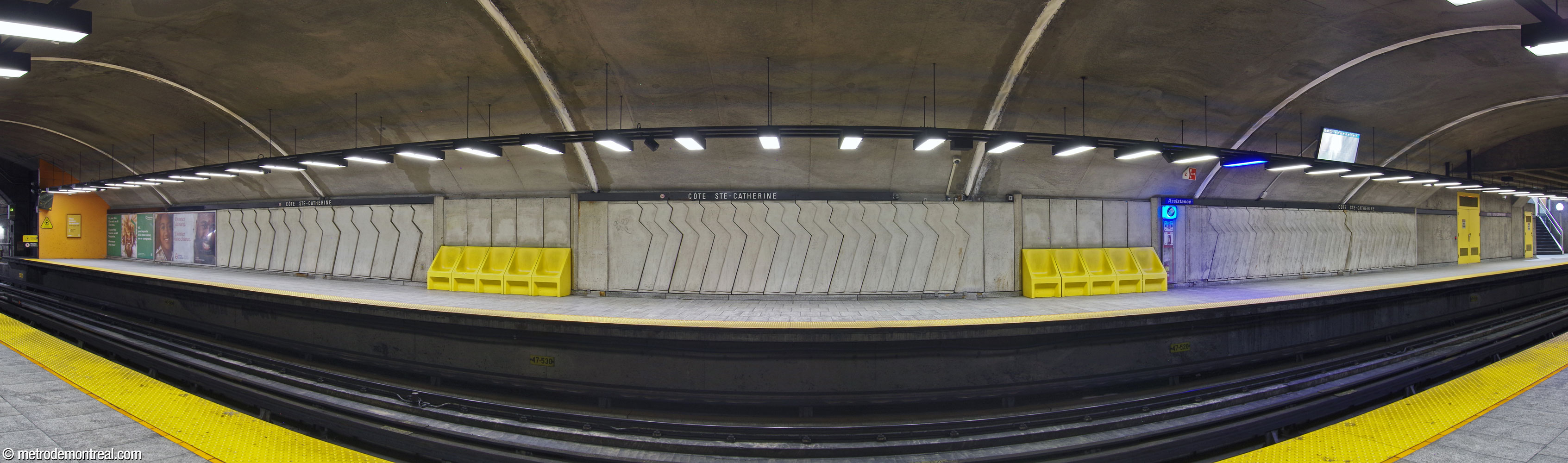 The head of the Côte-Vertu platform, showing the concrete frieze in the wall panels. The forms point the way to the stairs, and are more closely spaced the closer to the stairs one gets (here, from left to right). Note the ceiling lamps, set perpendicularly to the platform rather than in a parallel row as at most stations.