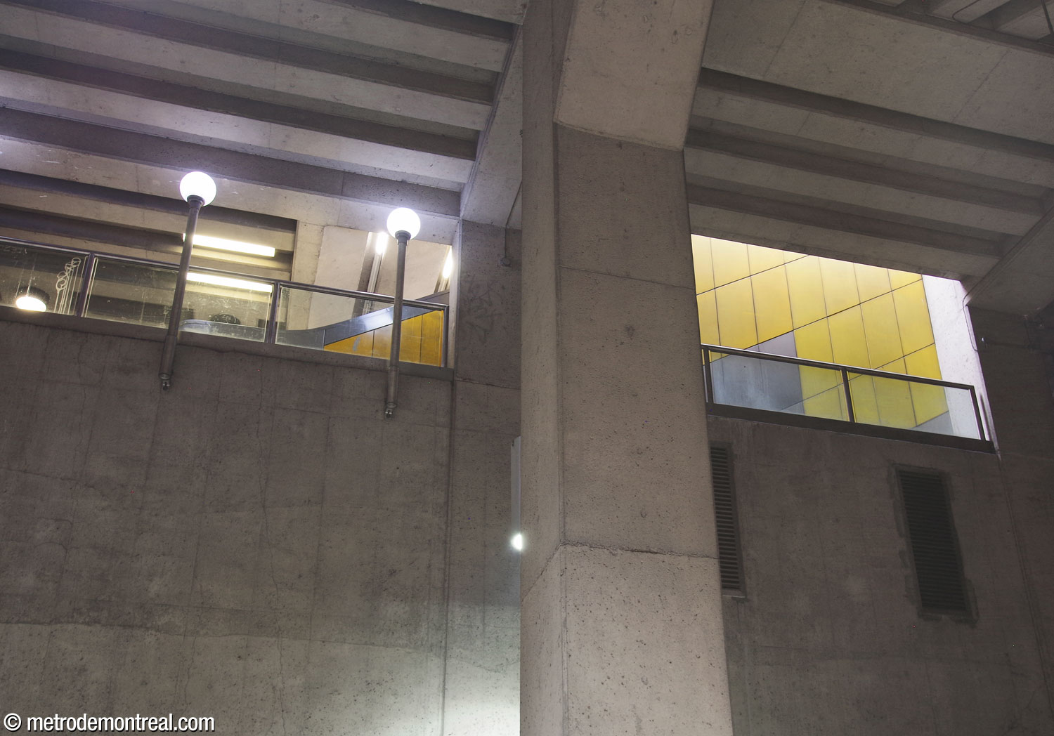 Like the main flight of escalators between the ticket hall and walkway, the escalators between the walkway and the headhouse are also decorated with an arrow-shaped mural of coloured panels by Gilbert Sauvé. This more discreet mural is only visible from below, looking up from the mezzanine.