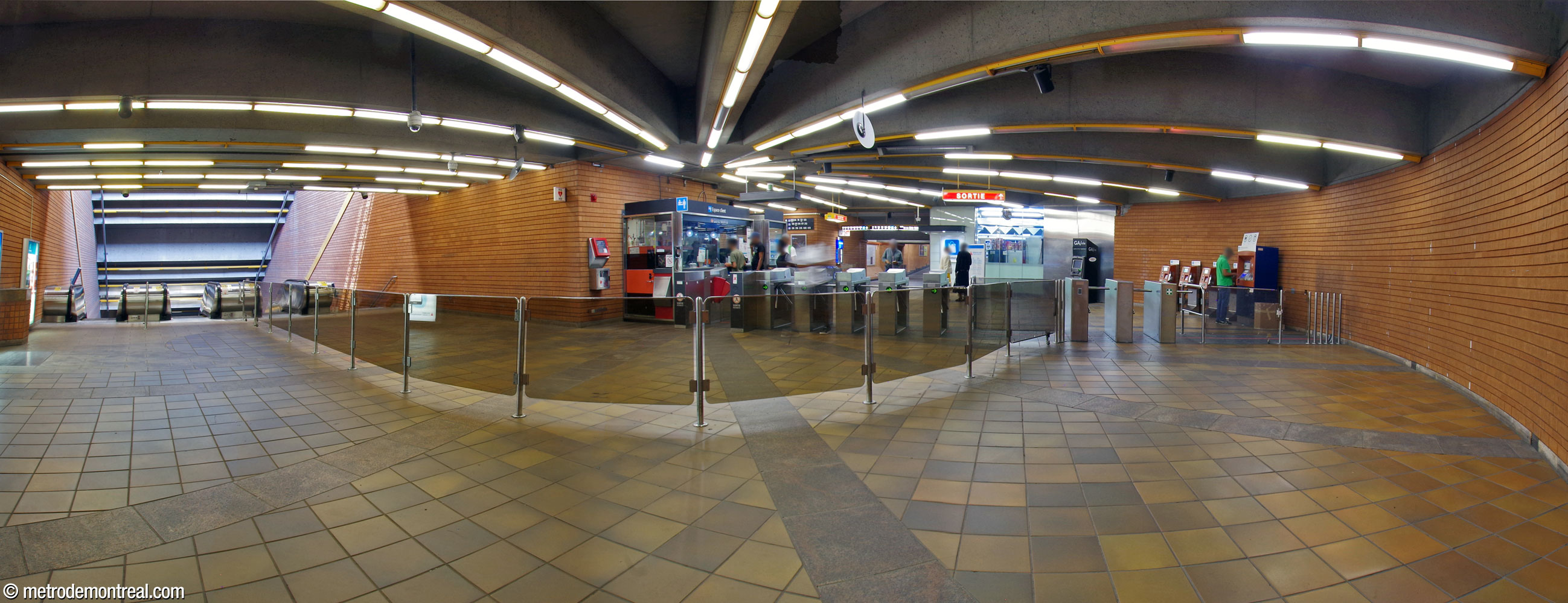 Panorama from the rear of the ticket hall emphasizing its semicircular plan, with a smooth curved path from the gateline (right) to the stairwell to the platforms (left). Note the barriers separating the traffic between entering and exiting passengers.