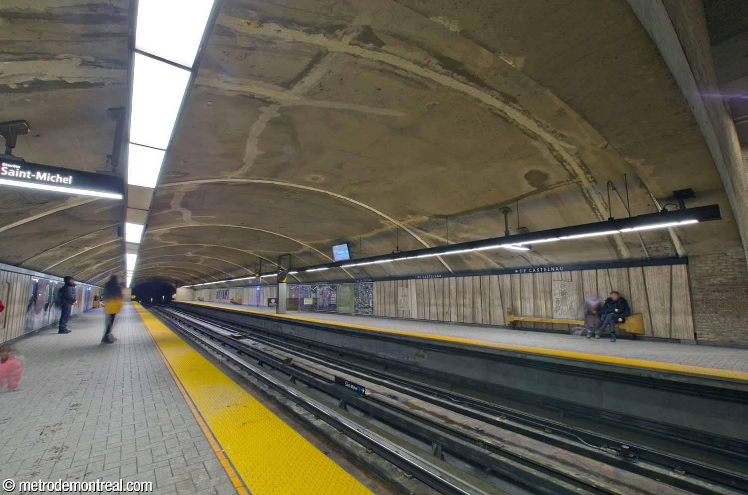 The mined portion of the trainroom extending west from the main volume, seen from the Saint-Michel platform. The walls are lined with irregularly shaped travertine panels.