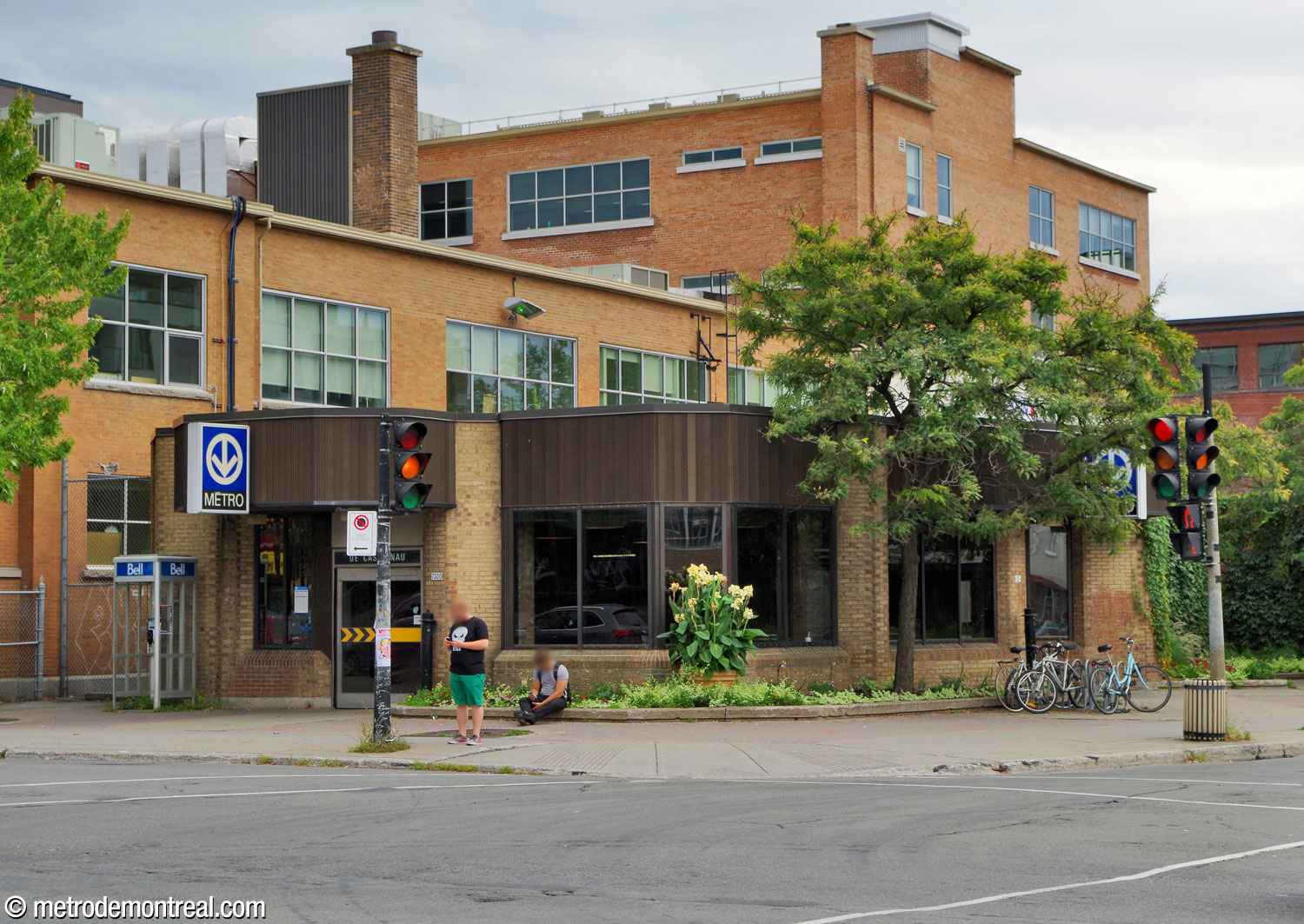 Exterior of the Saint-Laurent Ouest headhouse, with exits on the east and north sides. The low brick building features brown siding along the roof overhang and wide window bays.