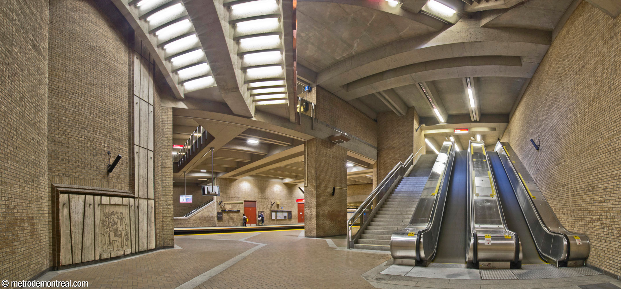 The side aisle of the Saint-Michel platform with the stairwell leading to the ticket hall. A bas-relief by Jean-Charles Charuest is seen on the travertine dado at left.