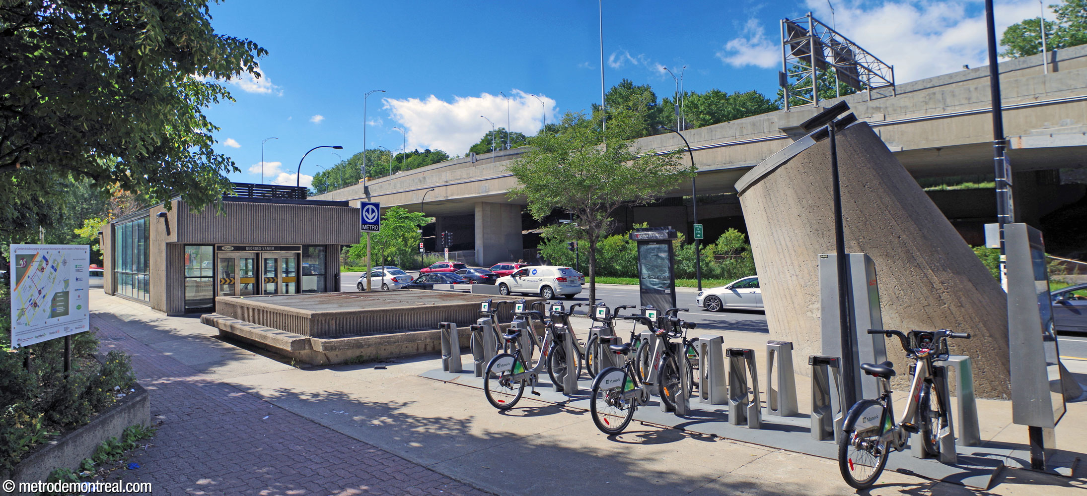 Exterior of the station headhouse (left), seen from the east. The exit faces a ventilation shaft (centre) and the frustum-shaped light shaft lantern (right).