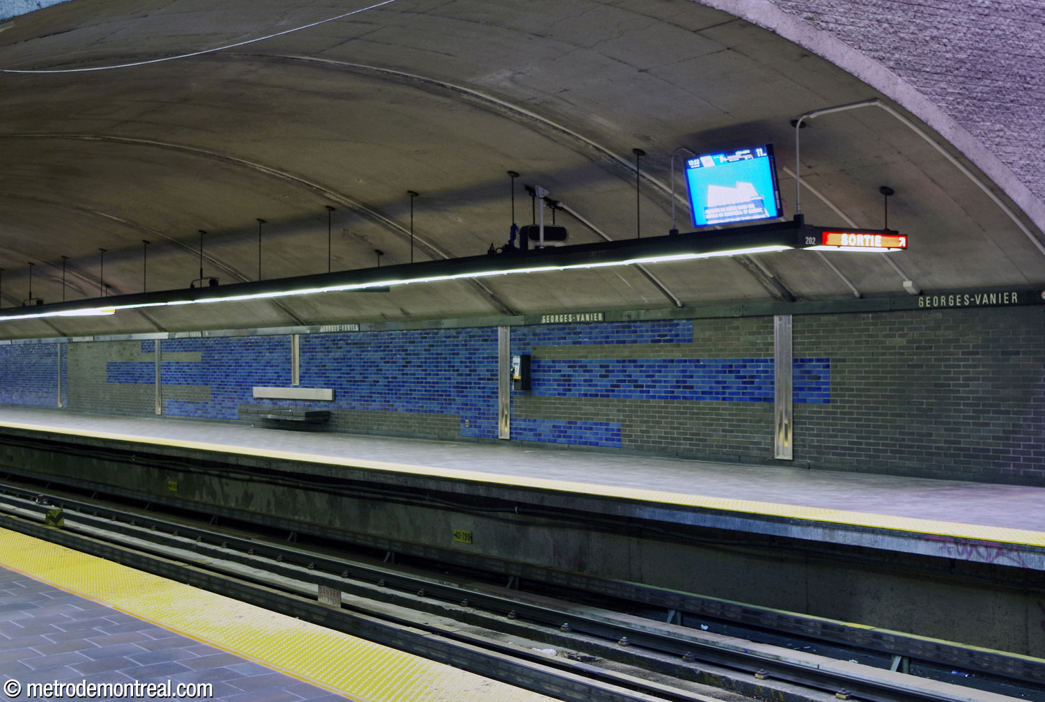 Horizontal motifs consisting of dark slate grey and blue glazed bricks decorate the walls of the parts of the trainroom built in tunnel. The benches consist of dark grey granite seats with stainless steel backrests.
