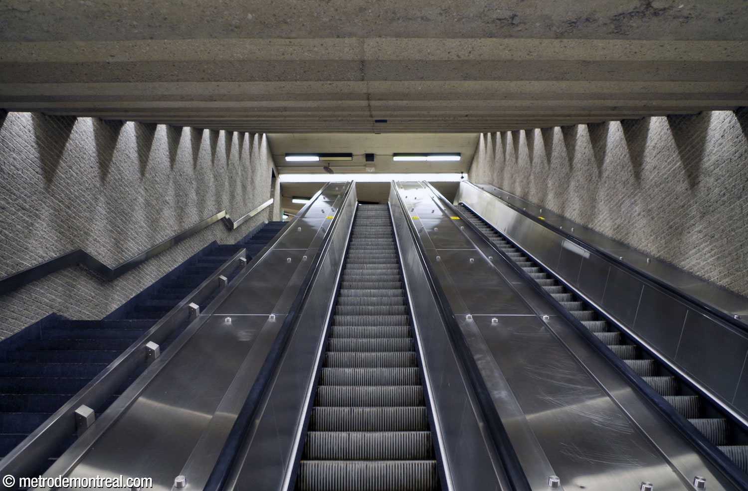 The stairwell between the ticket hall and transept levels. The arrangement of ceiling lights projects a play of light and shadow on the walls.
