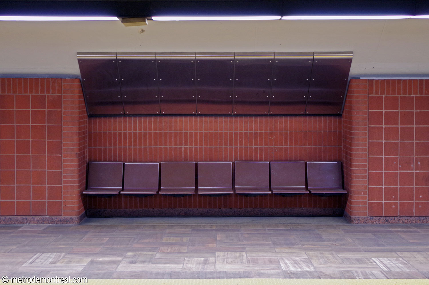 A niche containing seating in the original trainroom. The seats are in brown fibreglass. The walls are clad in terra cotta blocks, with edges and accents in rectangular ones and larger surfaces in square ones.