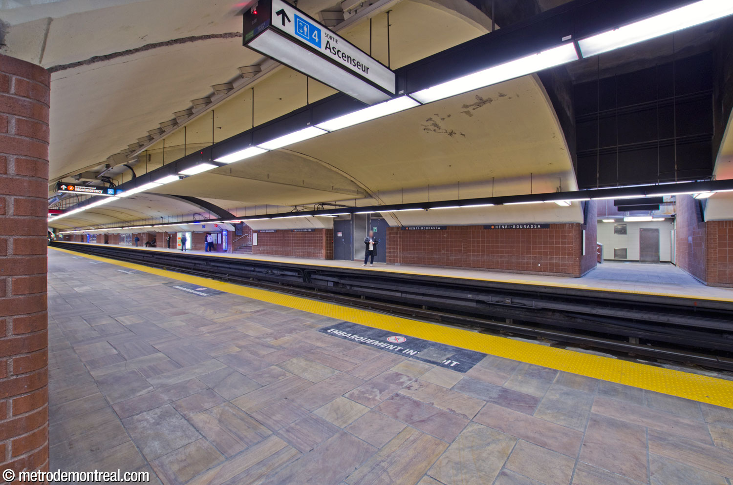 View of the original trainroom, looking south from the terminus platform. The crossover between the platforms is enclosed, and appears as a flat section of ceiling interrupting the trainroom vault (upper left and centre). In the foreground, the camera looks from one of the stairwells leading up to the crossover to its counterpart on the opposite platform, showing that they both occupy a narrow rectangular volume that also cuts the trainroom vault. The same is visible with the other pair of stairwells, in the background beyond the crossover.