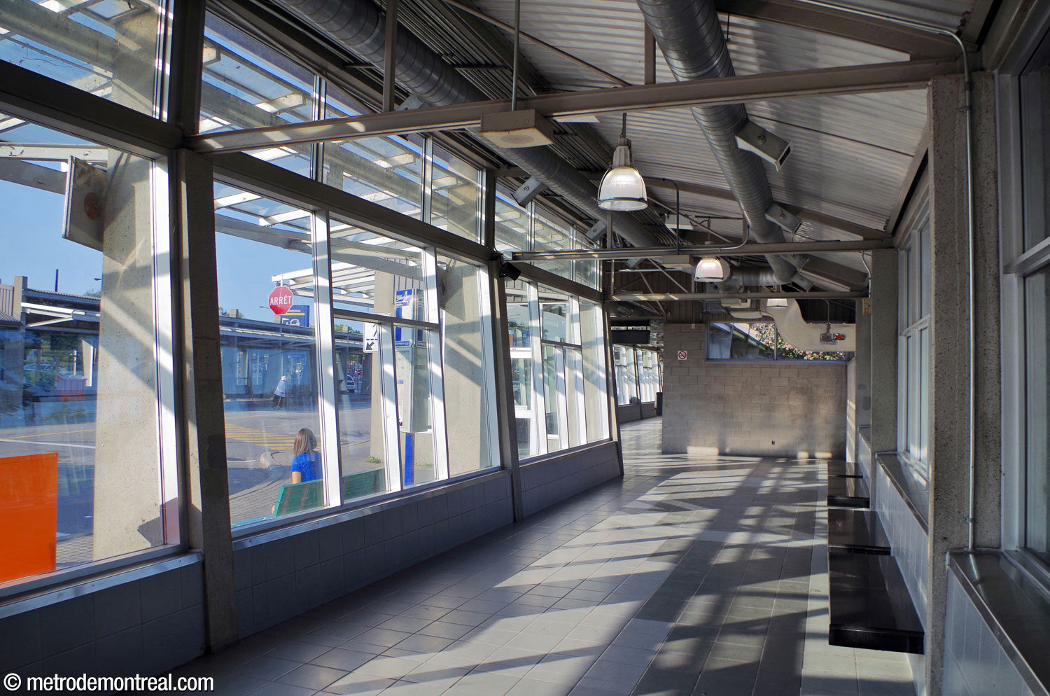 Interior of the south building of the bus terminal. Both the front and back walls of the concrete building are almost entirely glazed, with exposed framework and conduits on the ceiling.