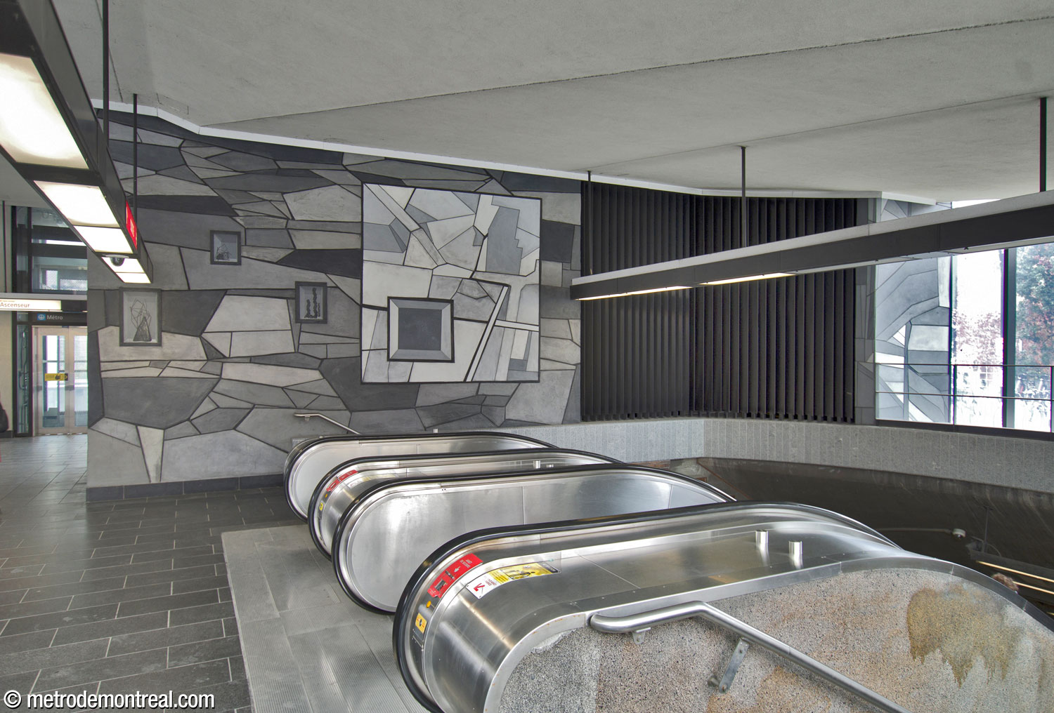 Une section de la murale de Simon Bilodeau, Je reviens chez nous, sur un mur au fond de l'édicule face à l'ouest, au-dessus de la cage d'escalier originelle. Le grand tableau représente un plan du Plateau aux débuts de son urbanisation. La petite section adjacente à la fenêtre, droite, représente l’un des escaliers en colimaçon emblématiques de Montréal.
