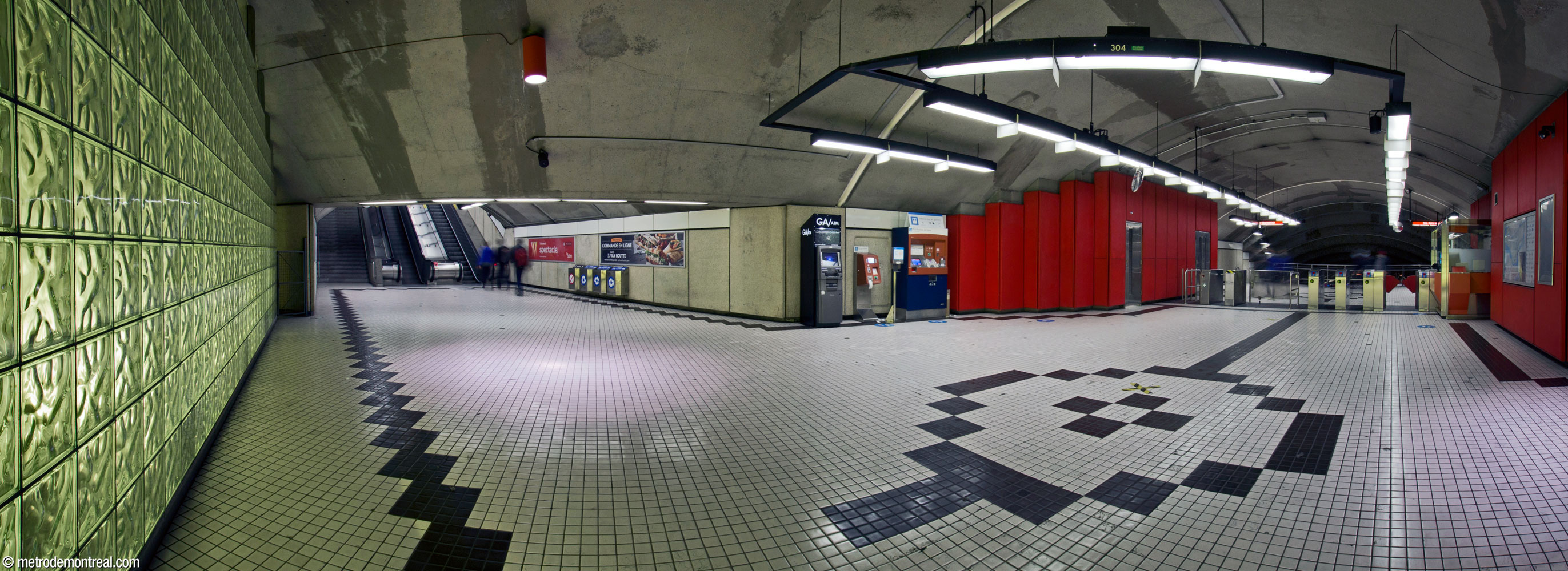 Panorama de la billetterie sud. À gauche, un mur de brique de verre rétroéclairé. Centre gauche, les escaliers vers la sortie Van Horne. Droite, les tourniquets et la loge du préposé, qui ressortent grâce aux panneaux muraux rouges.