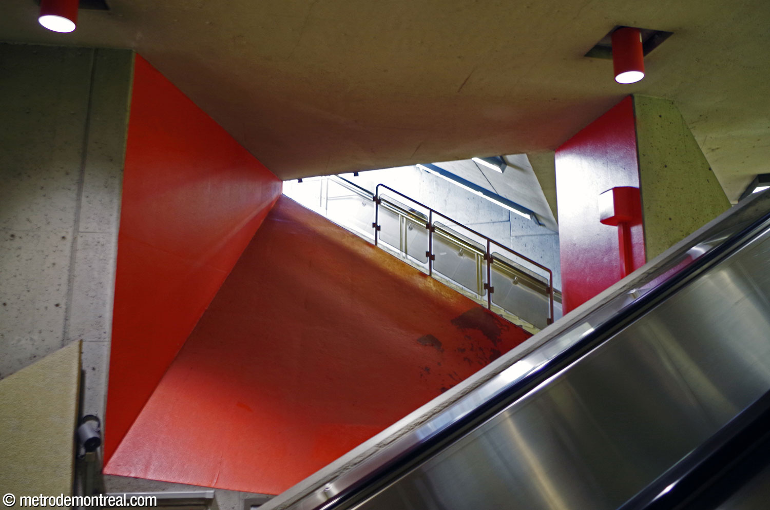 Des murs d'accent rouges ponctuent l'espace entre les escaliers au niveau du palier de l'accès sud.