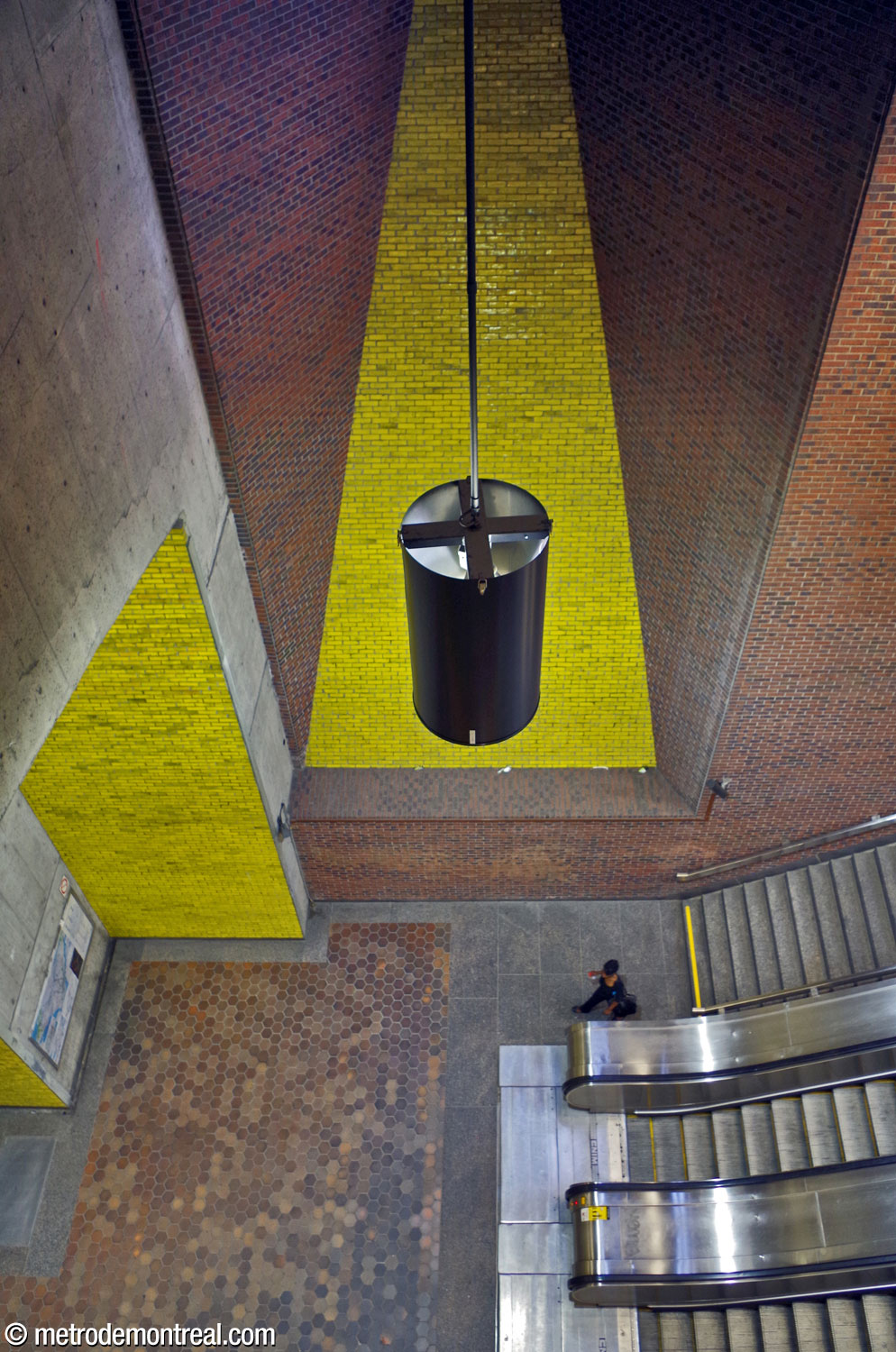 View of the foot of the escalators to the Montmorency platform from above, showing the tall light shaft over the platform level.