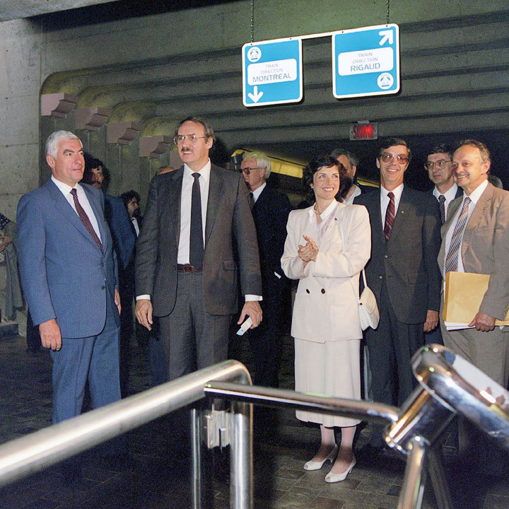La cérémonie d’inauguration de la gare de train de banlieue en 1985. Dans l’ordre habituel : Pierre Des Marais II, président du conseil d’administration de la CUM; Guy Tardif, ministre des transports du Québec; Louise Roy, présidente-directrice générale de la CTCUM; Jean-Paul Charland, directeur général des services à la clientèle; Grégoire Tremblay, commissaire; Jean-Jacques Bouvrette, directeur général de l’exploitation.