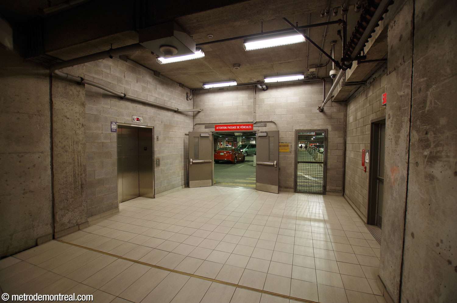 Le tunnel entre la billetterie initiale et la gare a été prolongé pour atteindre le campus du CUSM; il aboutit au mur du stationnement souterrain de l’hôpital. En attendant la complétion du nouvel édicule et de son tunnel vers l’hôpital, on a offert dans un premier temps un lien souterrain à travers ce stationnement. L’ascenseur (gauche) et les escaliers (derrière la porte à droite) mènent vers l’édicule sur le campus du CUSM.
