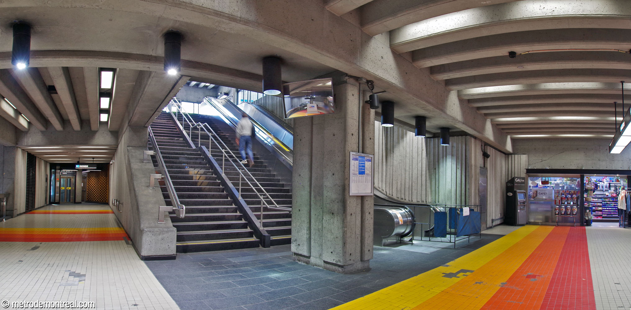 The fare-free portion of the ticket hall. At left, a walkway leads to the elevator up to the headhouse. At right, the stairs from the headhouse open toward the gateline (off camera at right).